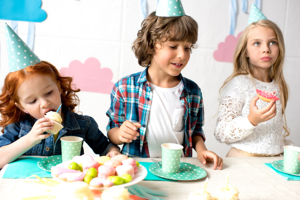 niños comiendo dulces en la mesa de cumpleaños
  - Foto, imagen