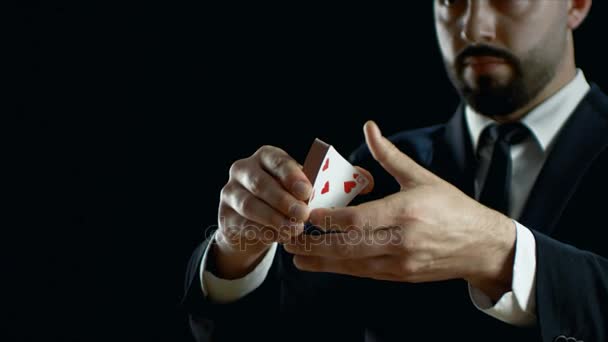 Close-up of a Professional Magician in a Black Suit Performing Card Trick. Throwing and Catching Cards Deck in the Air. Sleight of Hand. Background is Black. Slow Motion. - Imágenes, Vídeo