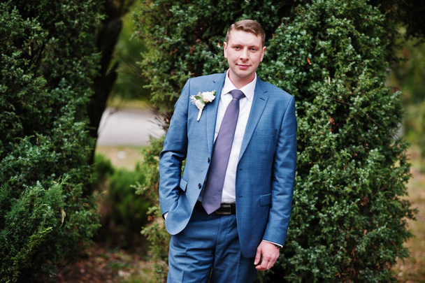 Portrait of a handsome groom posing in the park with trees on th - Photo, image