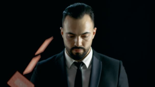 Close-up Portrait of a Bearded Magician Looking at the Camera and Gaming Cards Raining on Him then He Pulls Ace of the Deck. - Video, Çekim