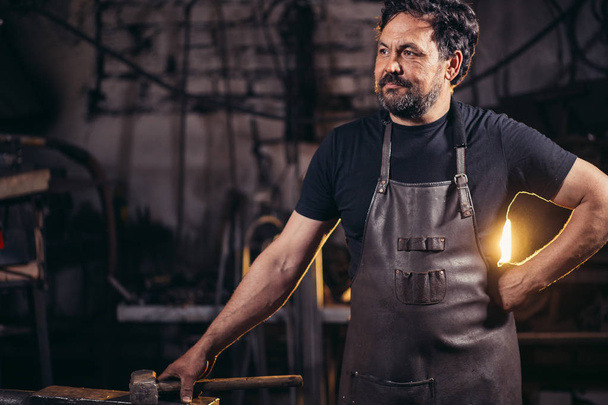 The portrait of blacksmith preparing to work metal on the anvil - Foto, Bild