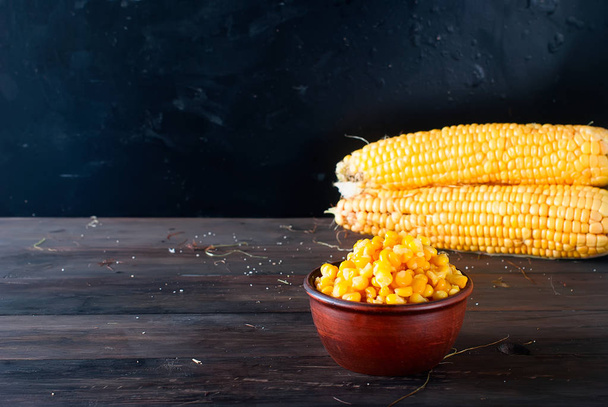 Fresh corn on cobs and bowl on rustic wooden table, closeup - Фото, изображение