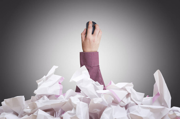 Computer mouse in businessman`s hand with crumpled paper pile.  - Photo, Image