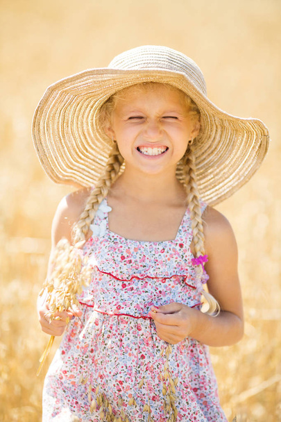 Little girl with blonde braids hair in a field. Little girl laughing, smiling - Photo, Image