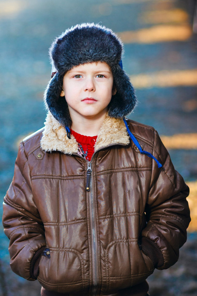 αγόρι με το καφέ σακάκι και γούνα καπέλο παντως μπλε αφηρημένη backg - Φωτογραφία, εικόνα