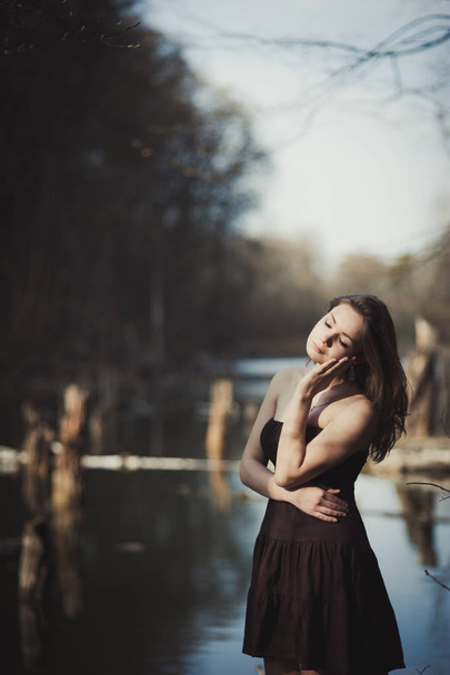 Brunette girl stands by the tree near the water - Foto, Bild