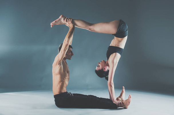 Young couple practicing acro yoga on mat in studio together. Acroyoga. Couple yoga. Partner yoga. - Valokuva, kuva