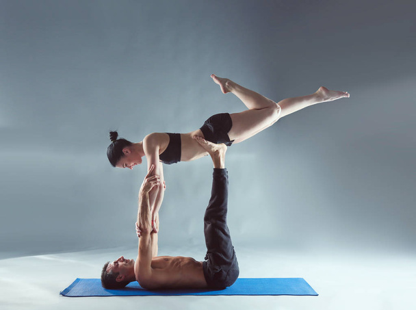 Young couple practicing acro yoga on mat in studio together. Acroyoga. Couple yoga. Partner yoga. - Valokuva, kuva