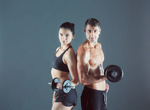 Спортивные мужчина и женщина с гантелями. Персональный тренер по фитнесу. Личное обучение
. - Фото, изображение