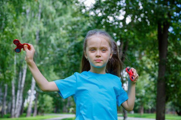 Little girl is playing with two spinners - Фото, изображение