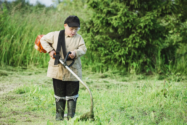 Jonge jongen maaien van gras - Foto, afbeelding