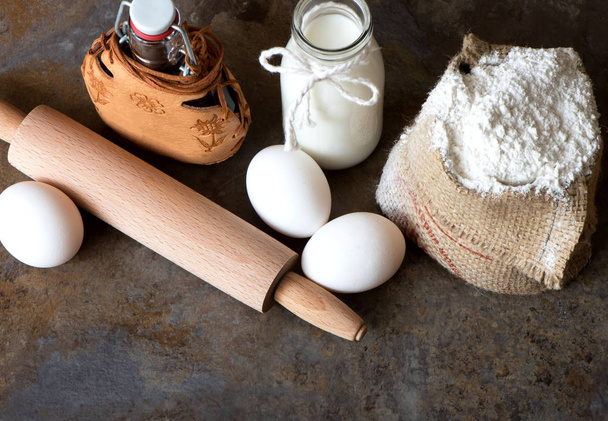 Ingrediënten voor het bakken - melk, eieren, meel, olie op bruin marmeren achtergrond. kopie ruimte - Foto, afbeelding