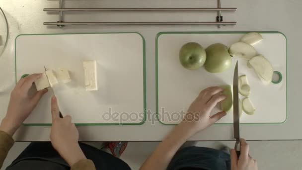 Діти вирізають яблуко та сир зверху. Діти маленька дівчинка і хлопчик готують на кухні
 - Кадри, відео