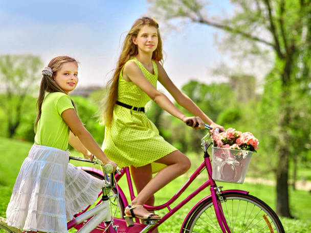 Girl wearing red polka dots dress rides bicycle into park. - Foto, imagen