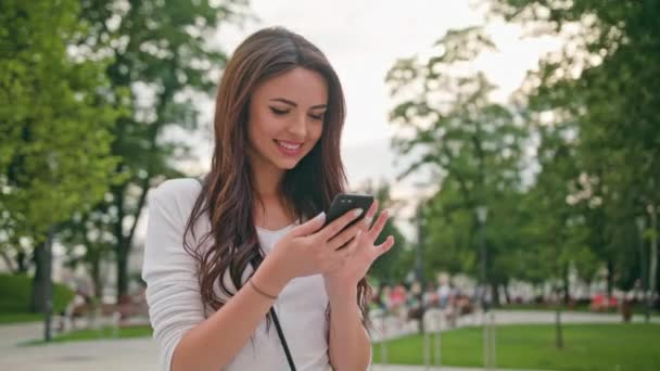 Egy gyönyörű barna használatával egy mobil telefon a szabadban - Felvétel, videó
