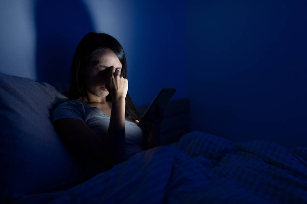 Женщина чувствует головную боль кровать с мобильного телефона
  - Фото, изображение