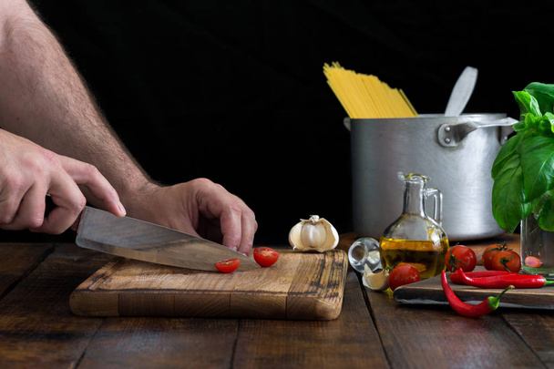 Hombre cocinando una pasta italiana sobre una mesa de madera
 - Foto, Imagen