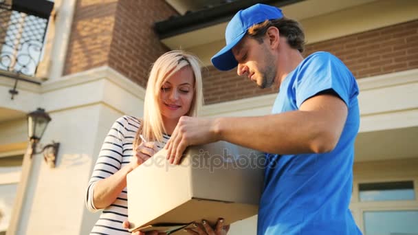 Attractive young woman signing the documents for getting package from the courier. View from the bottom. - Metraje, vídeo