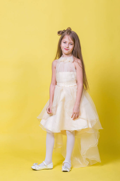Teenager girl in a dress on a yellow background poses for the camera - Fotografie, Obrázek