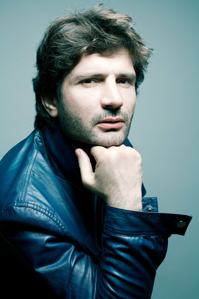 Portrait of a fashionable handsome man in blue jacket over light - Фото, зображення