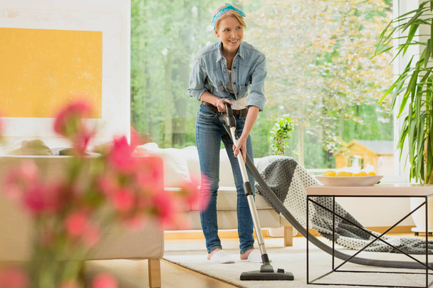 Woman is vacuuming beige carpet - Fotoğraf, Görsel
