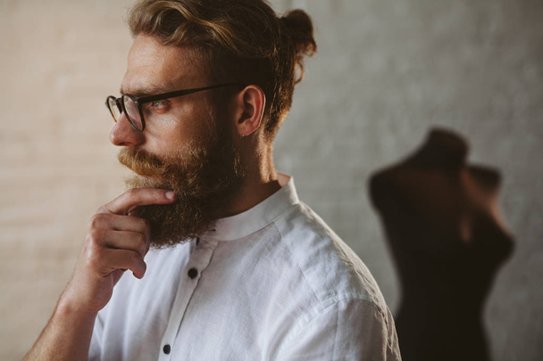 Bearded man wearing glasses touching chin - 写真・画像