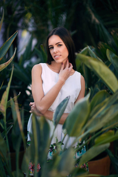 A beautiful and smiling woman. A thoughtful young lady. A girl in a white dress on a green summer park background. A sensual girl. - Foto, afbeelding