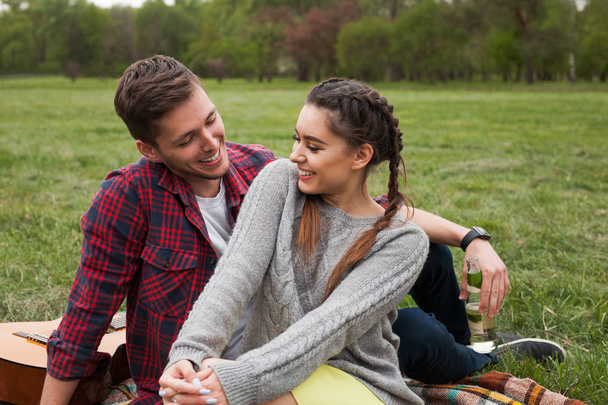 Smiling couple sitting on blanket in park. - Фото, зображення