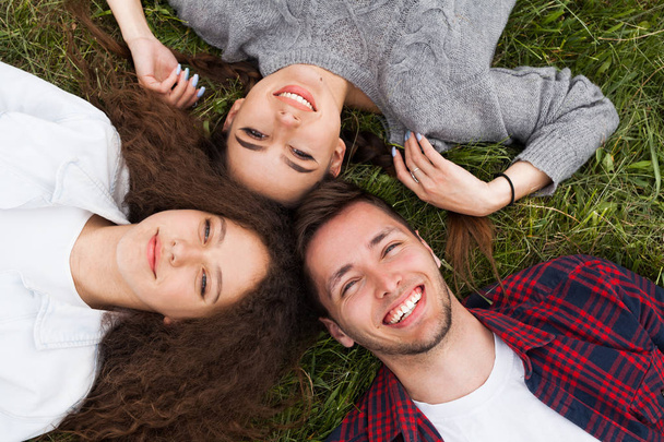 Two girls and guy lying on grass - Foto, Imagen