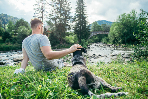 jeune homme fort reste près de montagne rivière avec chien et à la recherche de la vue
 - Photo, image