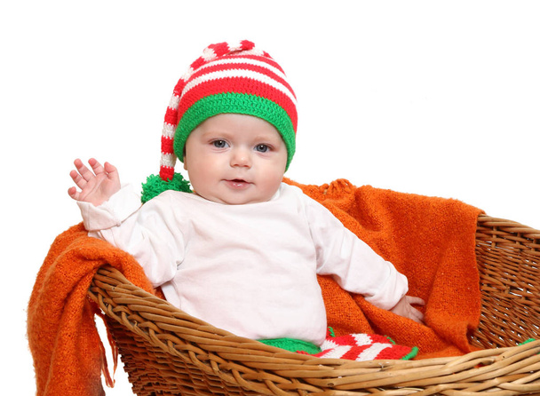 Malá holčička seděla v rustikální kočárek zdravení. Dítě, oblečený v domácí úplet pro chladné počasí jako vánoční kostým trpaslík.  - Fotografie, Obrázek