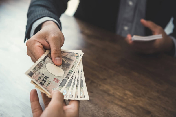 ビジネスマンの彼のパートナーに日本円紙幣のお金を与える - 写真・画像
