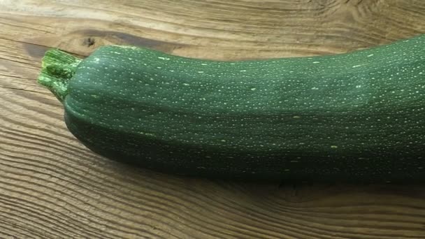 One whole zucchini (Cucurbita pepo) on a wooden background - Footage, Video