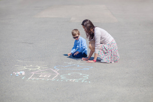 ママと小さな息子を道にクレヨンで描いています。. - 写真・画像