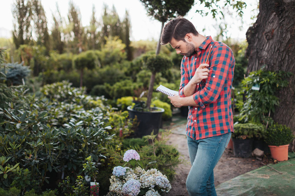 κηπουρός κάνοντας σημειώσεις στο Σημειωματάριο - Φωτογραφία, εικόνα