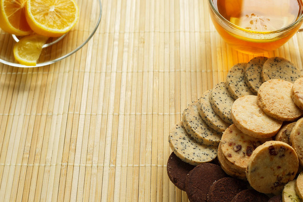 Tazza di tè di vetro con biscotti e limone su uno sfondo di legno leggero.Tazza di tè con limone e biscotti
 - Foto, immagini