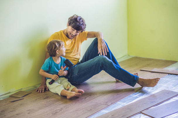Father and son installing  laminate flooring.  - Фото, изображение