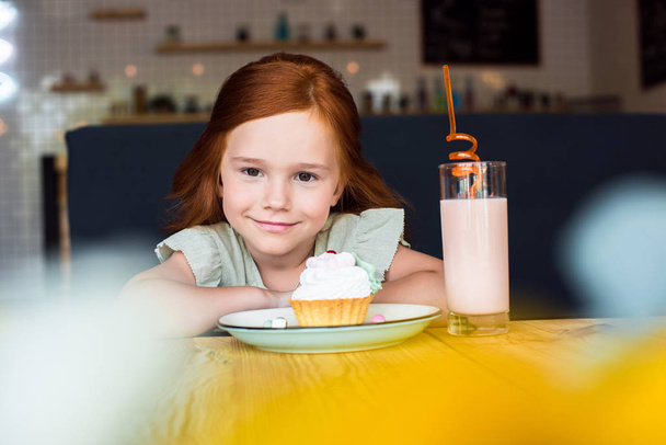 girl with cupcake and milkshake in cafe - Foto, afbeelding