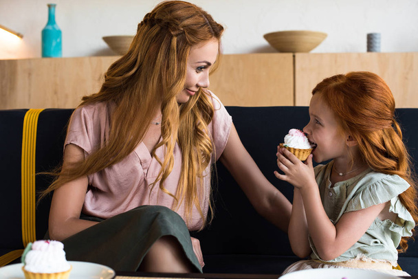 mother and daughter eating cupcakes in cafe - Fotoğraf, Görsel