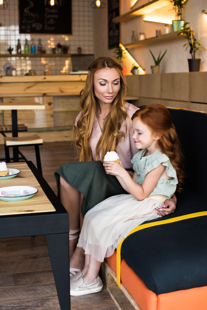 mother and daughter with cupcake in cafe - Фото, изображение