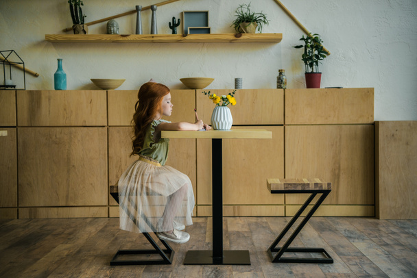 girl drawing at table in cafe   - Фото, зображення