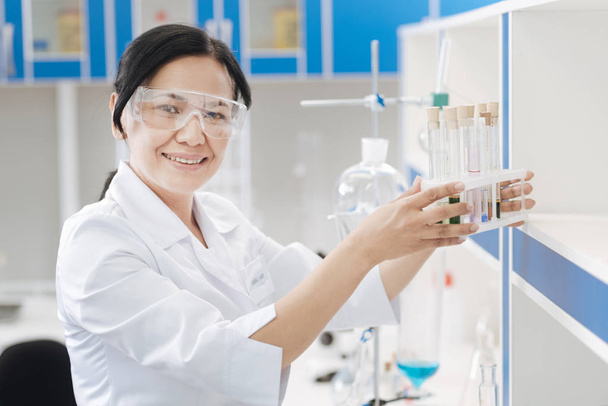Joyful nice chemist holding a test tube rack - Foto, Bild