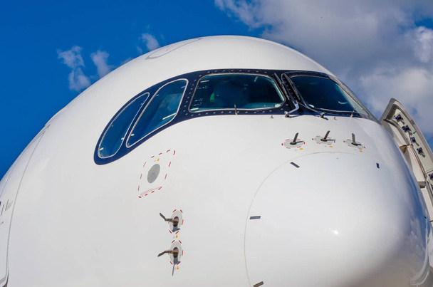 Matkustajien lentokoneen nenä ohjaamo sinisissä pilvissä taivas
 - Valokuva, kuva