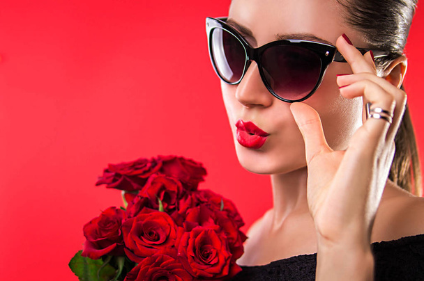 Красива жінка в сонцезахисних окулярах тримає троянди
 - Фото, зображення