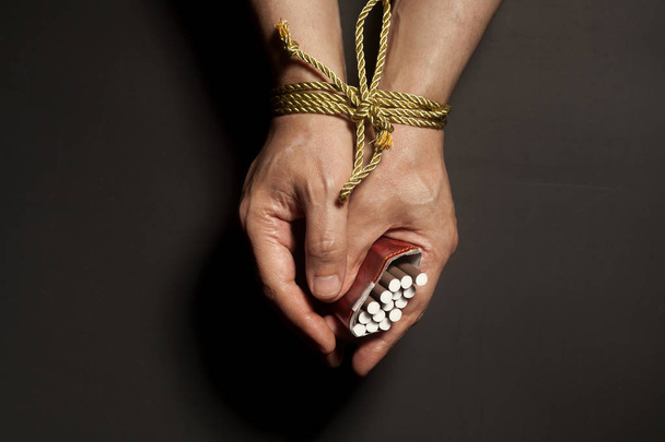 Tobacco addiction. Cigarettes on male hands tied with a rope - Φωτογραφία, εικόνα