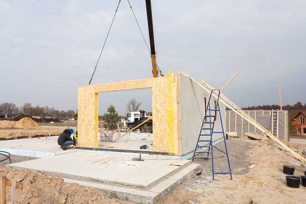 Tetőfedő építő munkások daru telepítése strukturális szigetelt panel Sip. Épület új keret energiatakarékos ház. - Fotó, kép