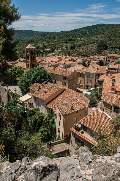 View of trees, house roofs and belfry under sunny blue sky in the charming village of Moustiers-Sainte-Marie.  - Foto, Imagem