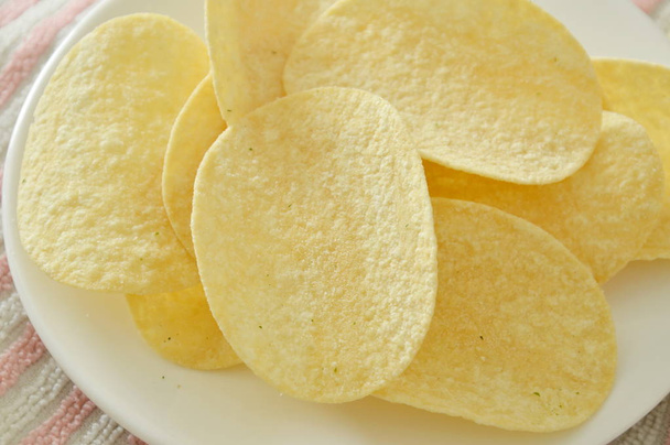  Хрустящие и соленые картофельные чипсы на тарелке
 - Фото, изображение