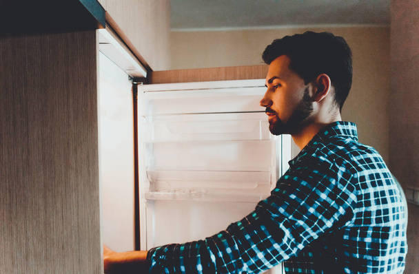 Молодой и успешный мужчина смотрит в холодильник
 - Фото, изображение