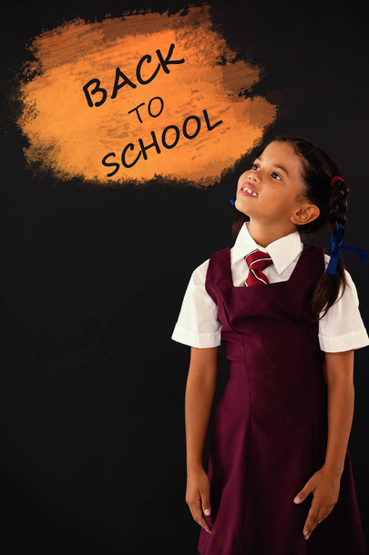schoolgirl standing against blackboard in classroom - 写真・画像